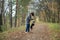 A happy and joyful boy walks with his buddy, a Boston terrier puppy, in a beautiful golden autumn forest.