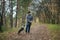 A happy and joyful boy walks with his buddy, a Boston terrier puppy, in a beautiful golden autumn forest.