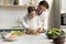 Happy joyful daddy teaching little daughter kid to cook salad