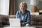 Happy joyful older pensioner woman using posing at computer