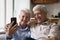 Happy joyful senior couple taking home selfie on mobile phone