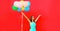 Happy joyful woman with bunch of colorful balloons raising her hands up on red background