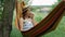 Happy joyful woman resting in hammock at green garden on weekend. Young woman lying in hammock and enjoying summer vacation at cou