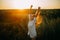 Happy joyful woman is walking on meadow at sunset