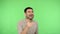 Happy joyous brunette man bursting into laughing and pointing to camera. green background, chroma key