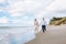 Happy just married middle age couple walk at beach against blue sky with clouns and have fun on summer day.