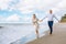 Happy just married middle age couple walk at beach against blue sky with clouns and have fun on summer day.