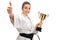 Happy karate girl giving thumb up and holding golden trophy