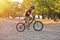 Happy kid boy of 7 years having fun in autumn park with a bicycle on beautiful fall day. Active child wearing bike helmet