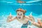 Happy kid boy swim and dive underwater, kid with thumbs up in swimpool. Active healthy lifestyle, water sport activity