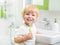 Happy kid or child brushing teeth in bathroom