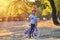 Happy kid girl of 7 years having fun in autumn park with a bicycle on beautiful fall day. Active child wearing bike helmet