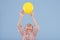 Happy kid girl holds up yellow balloon dressed in striped shirt,