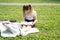 happy kid girl on school uniform with notebook has online lesson on laptop on lawn