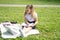 happy kid girl on school uniform with notebook has online lesson on laptop on lawn