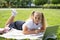 happy kid girl on school uniform with notebook has online lesson on laptop on lawn