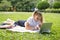 happy kid girl on school uniform with notebook has online lesson on laptop on lawn