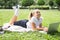 happy kid girl on school uniform with wireless headphone has online lesson on laptop on lawn