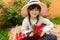Happy kid girl in straw hat with ukulele having fun on summer field.