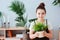 Happy kid girl taking care of houseplants at home, dressed in stylish black and white outfit