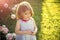 Happy kid having fun. Child with thinking face in blue dress at blossoming roses