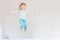 Happy kid jumping over bed. Cute little blond girl having fun indoors. Happy and careless childhood concept