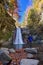 Happy kid near photo camera on tripod with a waterfall in background in autumn