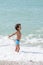 Happy kid playing on the beach in rough waters during a summer vacation