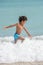 Happy kid playing on the beach in rough waters during a summer vacation