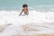 Happy kid playing on the beach in rough waters during a summer vacation