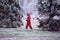Happy kid in red romper having fun, walking among frozen trees in winter park