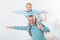 happy kid sitting on grandfather shoulders and imitating plane