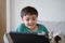 Happy Kid sitting on sofa having fun taking with his class friends on tablet, Child boy studying online on digital tablet, new