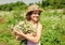 Happy kid smile in sun hat with chamomile flower bunch on sunny landscape vacation in countryside summertime, summer