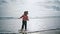 Happy kid walking ocean water in autumn sunlight. Joyful child playing waves