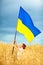 Happy kid waving ukrainian flag on wheat field