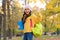Happy kid wear headphones in autumn park with book and backpack, school education