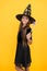 Happy kid wear witch hat holding magic wand to create enchantment on halloween, halloween magic