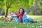 Happy kids boy and girl in rain rubber boots playing outside in the green park with blooming field of daisy flowers