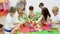 Happy kids and female teacher playing together with colorful toy building blocks in classroom at elementary school