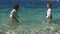 Happy kids have fun in the clear sea water. Boy and girl splash and laugh