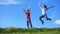 Happy kids jumping together on green grass hill against blue sky