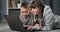 Happy kids lying on floor and playing games on laptop