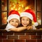 Happy kids in Santa hat look out window at