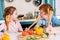 happy kids with wooden utensils smiling each other while cooking together