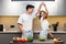 Happy Korean Couple Cooking And Having Fun Dancing In Kitchen