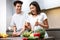 Happy Korean Couple Cooking And Laughing Preparing Dinner At Home