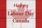 Happy Labour Day Canada message with Canadian maple leaf flag on wood