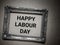 Happy Labour Day text on wall with wooden frame background