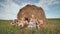 Happy large family sits near a sheaf of straw in the field.